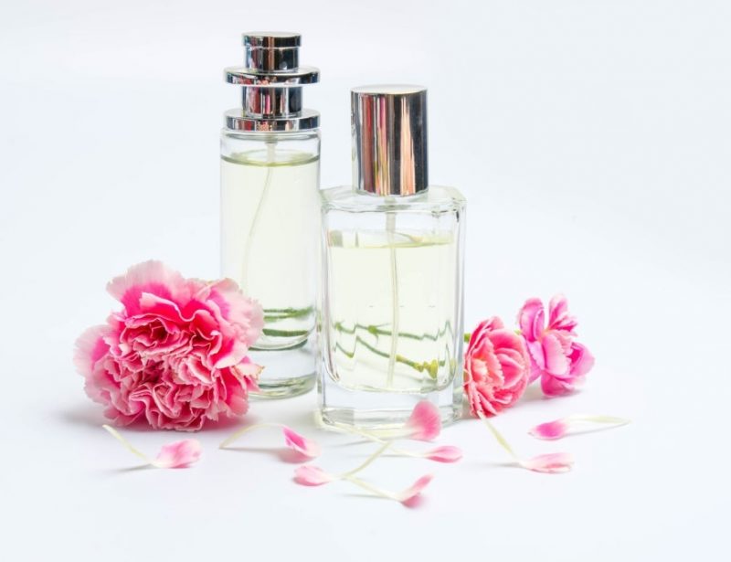 Beautiful perfume bottles  and pink carnations on white background
